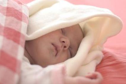 Младенец спит в розовой постели