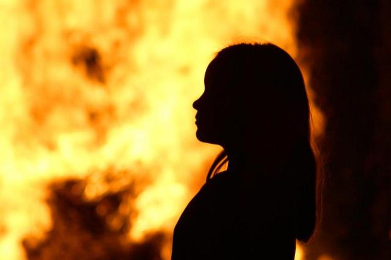 Силуэт девушки, стоящей против огня ночью