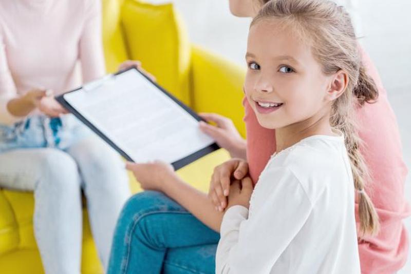 Ребенок улыбается возле матери и няни дома