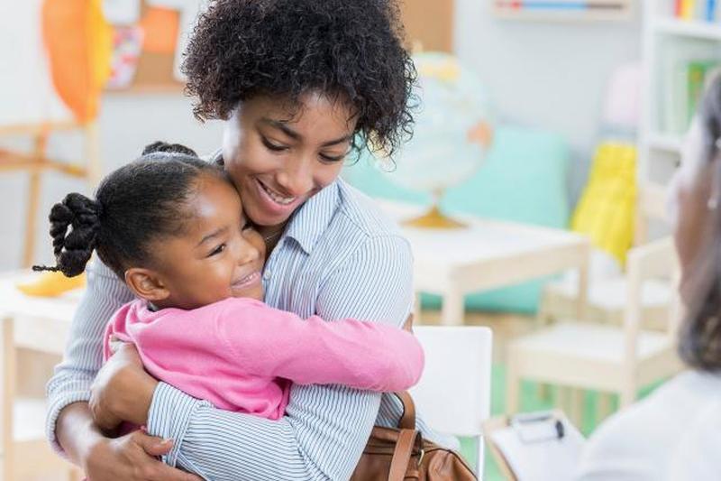Маленькая девочка обнимает мать во время собеседования в детском саду
