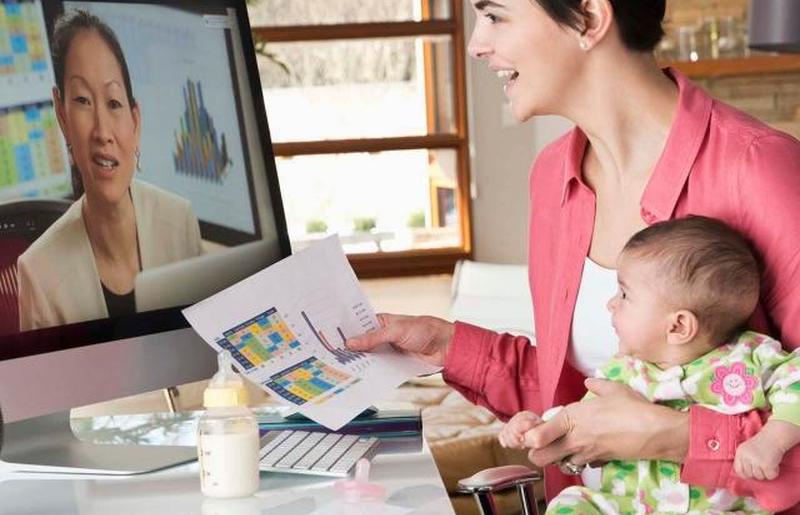 Мать держит дочь и работает из дома