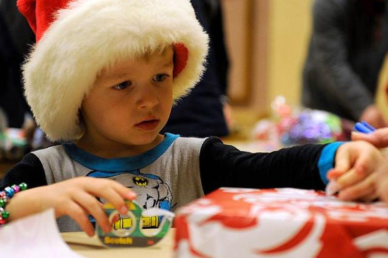 мальчик помогает упаковывать подарки во время операции Дед Мороз