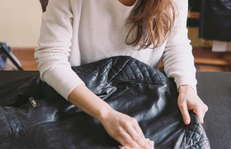 Женщина, чистящая кожаную куртку