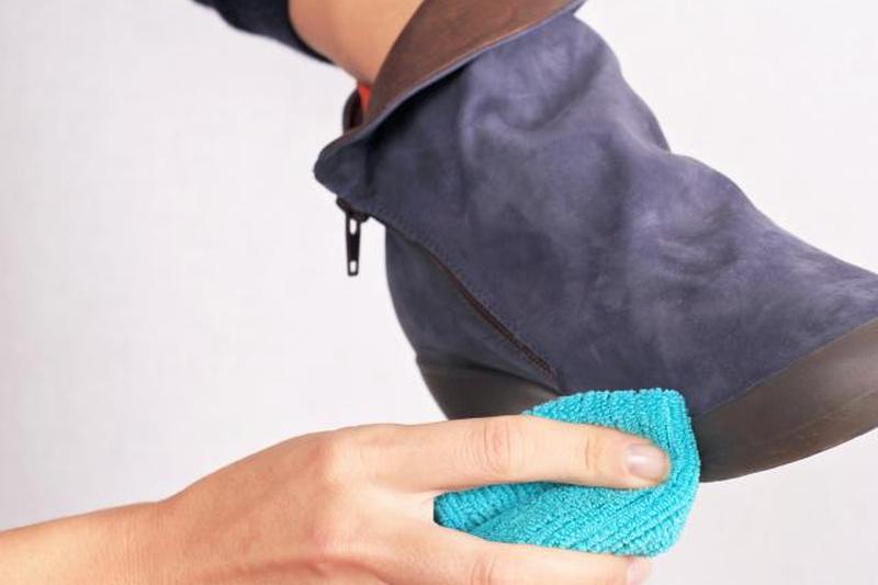 Женщина чистит замшевые сапоги для зимнего ухода