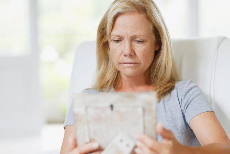 Грустная женщина, держащая фото