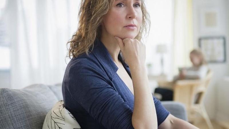 Обеспокоенная женщина, сидящая на диване