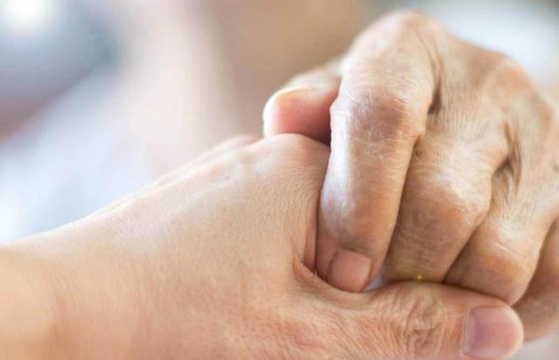 держит пожилую женщину за руку в хосписе