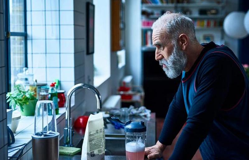 Печальный человек, опираясь на кухонную стойку