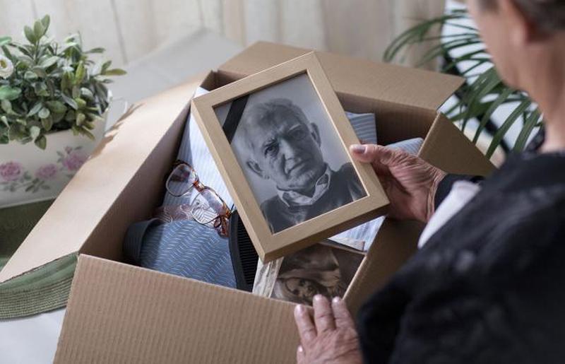 Женщина пакует вещи своего умершего мужа