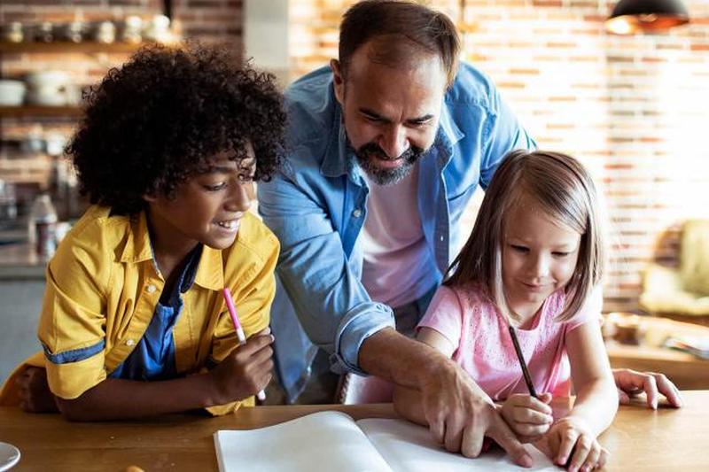 отец помогает своим детям с школьной работой