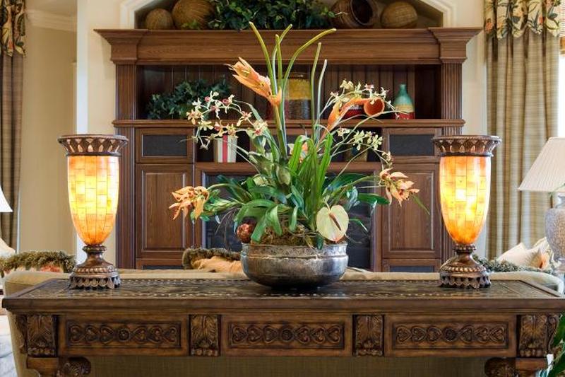 Красивый резной консольный столик с шелковым растением и светильниками в берлоге
