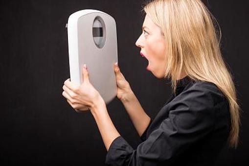 женщина в шоке смотрит на весы