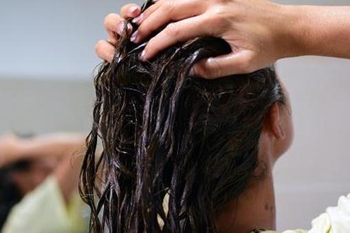 женщина наносит масло на волосы