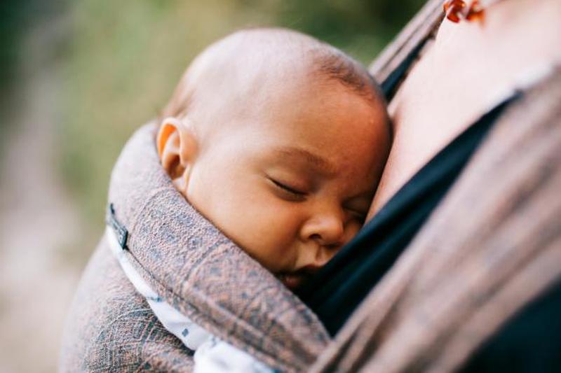 Мать несет спящую дочь в переноске