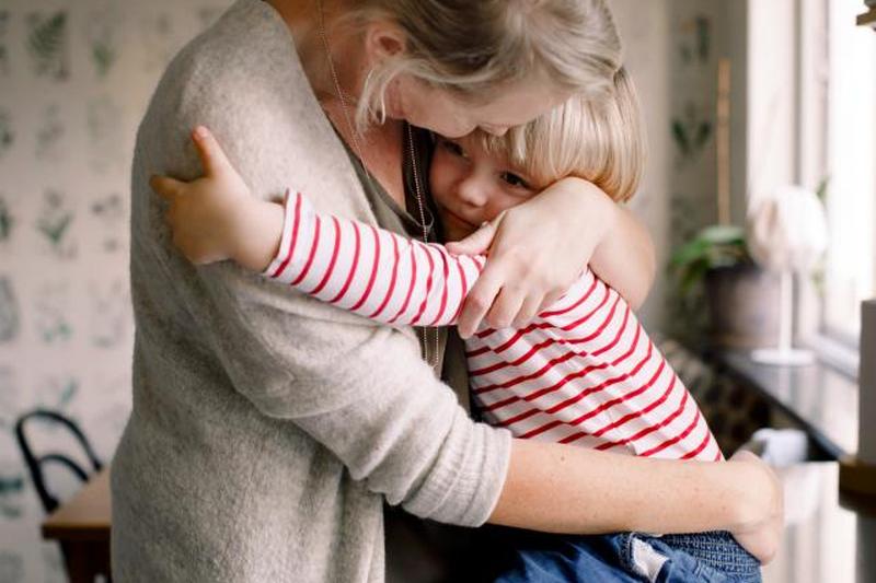 Любящая дочь обнимает мать, сидя на кухонном столе