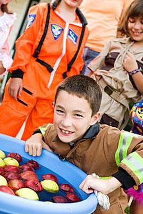 Дети ловят яблоки на вечеринке в честь Хэллоуина