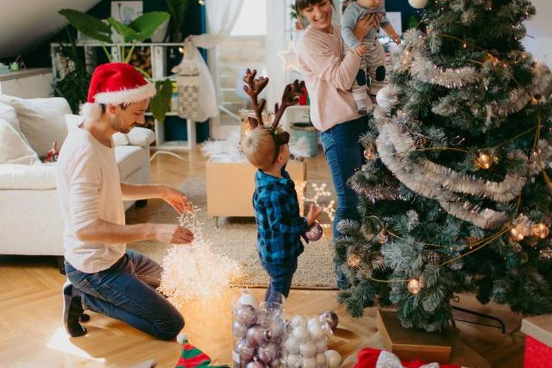 семья с двумя детьми, украшающая елку