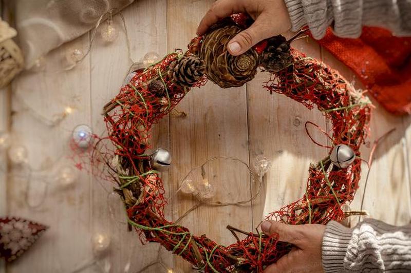 руки держат декоративный рождественский венок