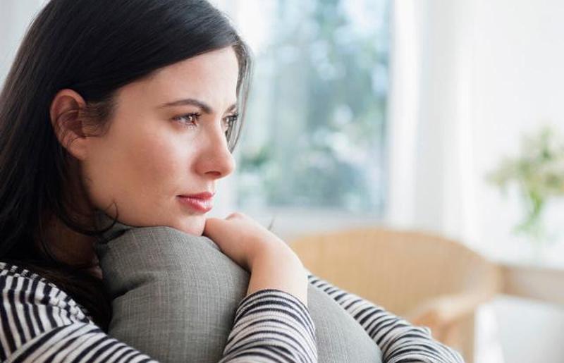 Задумчивая женщина сжимает подушку