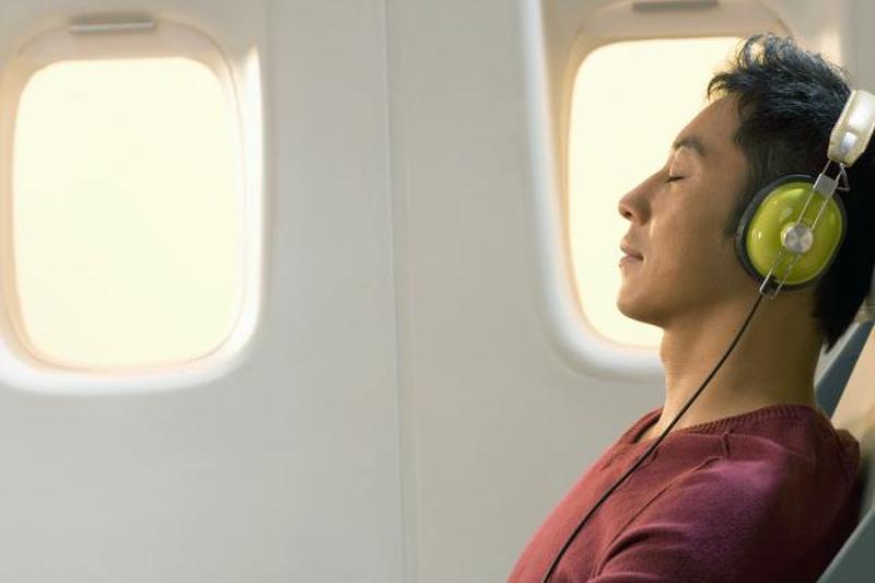 Мужчина отдыхает и слушает музыку в самолете