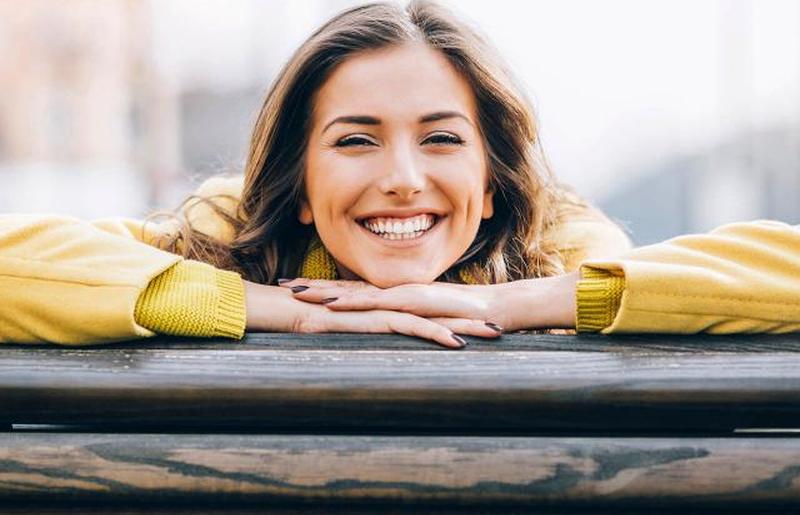 Улыбающаяся молодая женщина сидит на скамейке